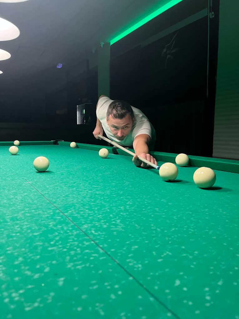 Игрок выполняет удар на столе для русской пирамиды в Billard O.
